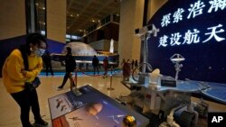 资料照片:2021年3月12日,一名参观者在北京观看中国天问一号飞船火星探测器复制品的展览。(美联社照片)