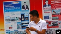 2018年8月22日,北京地铁站外的政府宣传广告牌宣传中国国家主席习近平和中国的经济成就,一名男子站在旁边。