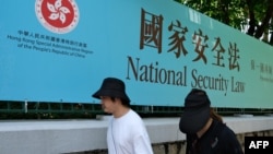 行人走过香港街头港版国安法的宣传牌。(2020年7月15日)
