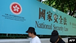 行人走过香港街头港版国安法的宣传牌。(2020年7月15日)