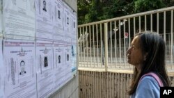 资料照片:一名行人在香港观看警方为以涉及违反国安法的罪名对八名居住在美国、英国、加拿大和澳大利亚发出的通缉令。(2023年7月14日)