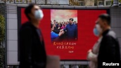 戴着口罩的行人走过上海街头宣传习近平的宣传画。(2020年3月23日)