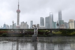 台风“烟花”正在逼近上海,一位男子冒雨走在黄浦江边的外滩。(路透社照片)