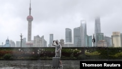 台风“烟花”正在逼近上海,一位男子冒雨走在黄浦江边的外滩。(路透社照片)