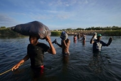 包括很多海地人在内的移民离开德克萨斯州的德尔里奥,淌水越过格兰德河,返回墨西哥一侧,有些人是为了躲避美国遣返,有些人则是为了补充物资。(2021年9月22日)