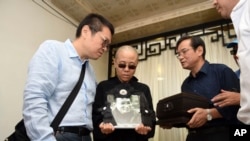 诺贝尔和平奖得主刘晓波的遗孀刘霞(中)在中国辽宁省沈阳举行的刘晓波葬礼期间手捧丈夫刘晓波的遗像。(2017年7月15日)