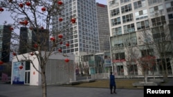 疫情期间,一位戴口罩的女性在北京市中心商业区一座商业大楼前走过。(2020年2月18日)