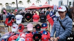 2024年1月7日,总统大选前一周,高雄,一名街头小贩在主要反对党国民党的竞选集会上出售旗帜和帽子。(法新社)