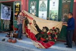 北京商贩正在展示一面画有中国前领导人毛泽东在文革时期的宣传旗。(2016年5月16日)