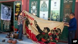 北京商贩正在展示一面画有中国前领导人毛泽东在文革时期的宣传画。(2016年5月16日)