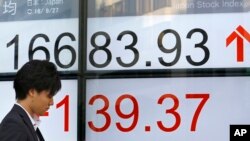 一名男子站在东京一家股票交易所的显示屏前。(2016年9月27日)