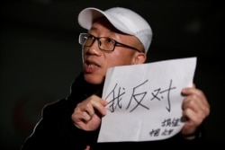 2018年2月28日,在北京接受路透社采访时,中国维权人士胡佳手持标语“我反对”。(2018年2月28日)