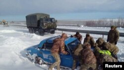 资料照片:乌克兰军人在敖德萨地区帮助一辆陷在大雪中的汽车脱险。(2023年11月28日)