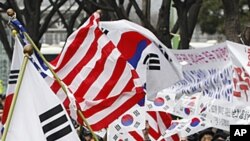 3月14号,韩国的些支持者在美国驻首尔大使馆前挥舞美韩两国国旗,欢呼双方签署自由贸易协定。