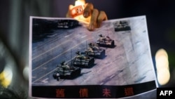 在香港维多利亚公园参加纪念六四事件31周年的一名男子手持天安门广场“坦克人”的照片。(2020年6月4日)
