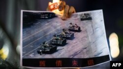 在香港维多利亚公园参加纪念六四事件31周年的一名男子手持天安门广场“坦克人”的照片。(2020年6月4日)