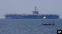 一艘小渔船从停靠在菲律宾马尼拉的美国海军卡尔文森号航空母舰附近驶过。(2018年2月17日