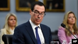 美国财政部长姆努钦(Steven Mnuchin)在华盛顿国会山作证时阅读手机上的一条信息(2020年3月11日)。