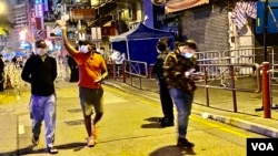 香港政府宣布1月25日傍晚6时开始,持阴性病毒检测证明的人士,可以登记离开佐敦封锁区,被禁足接近40小时的居民重获自由后离开封锁区时向传媒挥手。 (美国之音/汤惠芸)