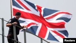 英国皇家海军海神之子两栖登陆舰抵达日本东京一个港口时一名英国水手站在英国国旗前。(2018年8月3日)