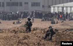 以色列士兵在加沙地带的以色列一边注视着巴勒斯坦抗议者。 (2018年5月14日)