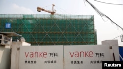 上海一栋建筑工地门口悬挂着万科标志。万科总裁传被公安带走的消息传出后,星期五股价暴跌逾8%。(路透社:2017年3月21日)