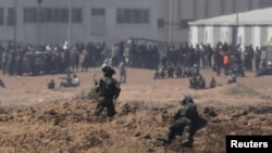 以色列士兵在加沙地带的以色列一边注视着巴勒斯坦抗议者。 (2018年5月14日)