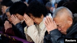 信众们在天津一个地下天主教堂祈祷(路透社)