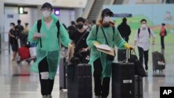 身穿防护服和戴口罩的旅客抵达香港国际机场。(2020年3月23日)