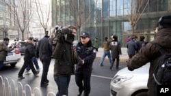 资料照片:中国政府加大对外国记者的压制。图为2014年1月26日,警察阻止在北京的外国记者采访受审的法律维权人士许志永的辩护律师张庆方。