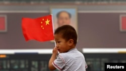 在天安门毛主席像前,小男孩举着中国国旗。在这个小男孩的有生之年,天安门毛像会拆除吗