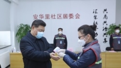 中国国家主席习近平戴着口罩视察北京安华里小区时一名防疫人员检测他的体温。(2020年2月10日)