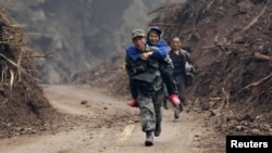 2013年4月22日,在宝兴县灵官镇外的一条刚刚被清理出来的道路上,一名解放军战士背着一位60岁的老大娘脱离险区。