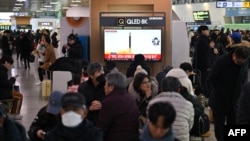 2024年1月14日,在首尔的一个火车站,人们正在观看电视屏幕上播放的朝鲜导弹试射的新闻片段。(法新社)