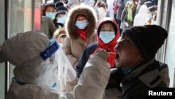 河北省石家庄一名身穿防护服的医护人员在给居民做病毒核酸检测。(2021年1月6日)