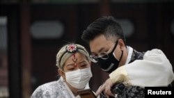 在韩国首尔市中心的景福宫,一对戴着口罩的情侣在看手机。(2020年3月1日)