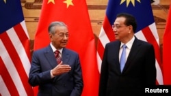 马来西亚总理马哈蒂尔(左)与中国总理李克强在北京人大会堂的签约仪式上。(2018年8月20日)