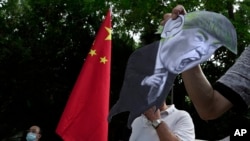 因美国制裁,支持中国的抗议者在美国驻香港领事馆外,手举美国总统唐纳德·特朗普的照片以示抗议。2020年8月8日图片。