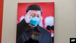 资料照片:2021年1月23日,武汉封城一周年当日,一名戴口罩儿童在武汉抗疫展览的习近平巨像前。(美联社Ng Han Guan拍摄图片)