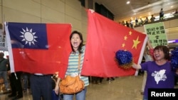 亲中国的台湾活动人士在桃园机场手举中国和台湾旗帜欢迎大陆海协会会长张志军访问台湾。(2014年6月25日)