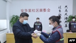 中国国家主席习近平戴着口罩视察北京安华里小区时一名防疫人员检测他的体温。(2020年2月10日)