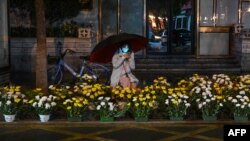 2023年1月21日,中国中部湖北省武汉市,一名沿街卖花的妇女在农历新年前夕等待顾客。