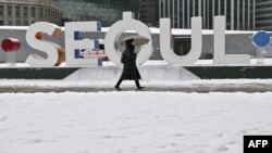 韩国首尔一名女子走过降雪的城市街头。(2023年1月26日)