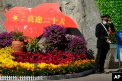 一名保安站在北京街头一处庆祝中共二十大的花坛旁。(2022年10月9日)