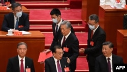 2022年10月22日,在北京人民大会堂举行的中共二十大闭幕式上,习近平看着前中共总书记胡锦涛被警卫扶着离席时拍了一下中国总理李克强的臂膀。