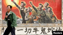资料照:一名男子走过宁夏银川街头郊区的一处描写中国文革的宣传画。(2007年4月25日)