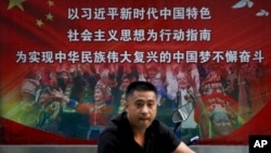 一名男子走过北京街头宣传习近平指示的各族人民大团结中国梦的广告牌。(20218年9月11日)