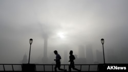 晨练者在上海外滩顶着浓雾和烟尘锻炼,远处隐约可见黄浦江对岸浦东金融区。美联社资料照