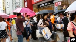 中国游客手提货物,在日本东京银座街道上等待旅游车。(2015年6月17号)