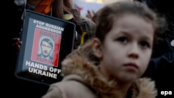 На той час президент Росії Володимир Путін ще називав російських «зелених чоловічків» на українському півострові «самообороною Криму». Акція протесту у столиці Чехії проти окупації частини території України, Прага, 8 березня 2014 року (ілюстраційне фото)